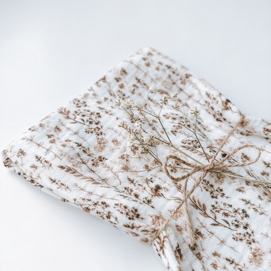 pieluszka muślinowa w kolorze bieli w suche trawy