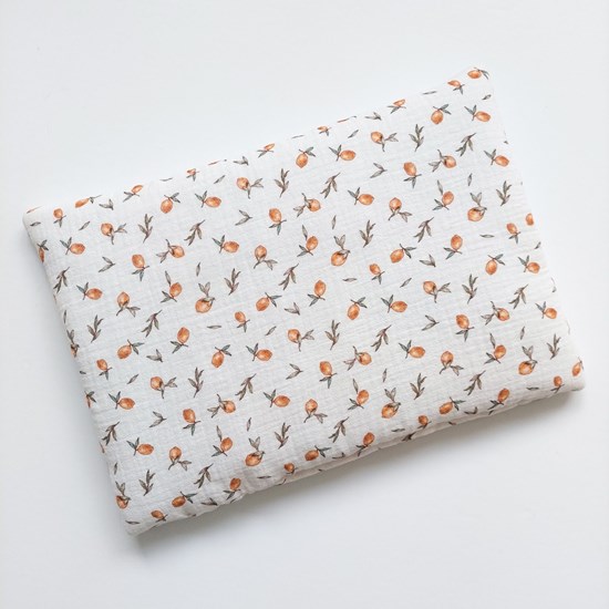 otulacz muślinowy w kolorze zgaszonej zieleni i poduszka w cytrynki