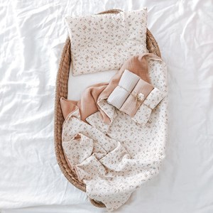 kocyk muślinowy w kolorze różu oraz wzór w kwiatuszki na beżu