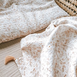 otulacz z bawełny muślinowej w kolorze bieli w kwiatuszki z czterema mini chwostami w kolorze beżu