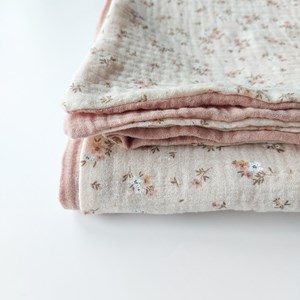 kocyk muślinowy w kolorze różu oraz wzór w kwiatuszki na beżu